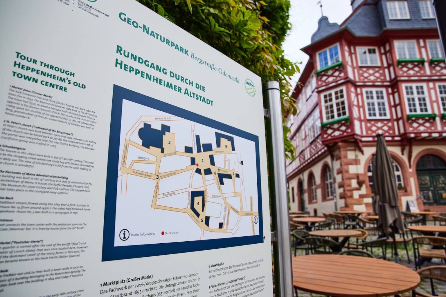 IDEE Living - Karte der Heppenheimer Altstadt auf einer Informationstafel vor einem historischen Fachwerkhaus mit Blick auf die Sitzgelegenheiten im Freien.