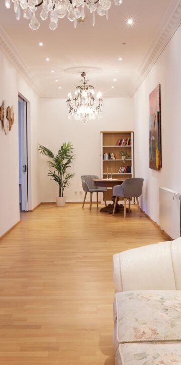 IDEE Living - Ein Wohnzimmer mit einer weißen Couch und einem Kronleuchter.