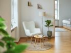 mannheim01_37 IDEE Living - Ein weißer Stuhl in einem Zimmer mit einem Bett und einer Pflanze.