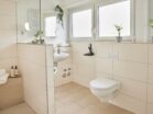 IDEE Living - Ein Badezimmer mit Toilette, Waschbecken und Fenster.